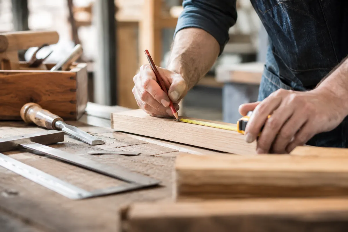 Gros plan sur la prise en main d'une perceuse visseuse pour assembler deux planches en bois